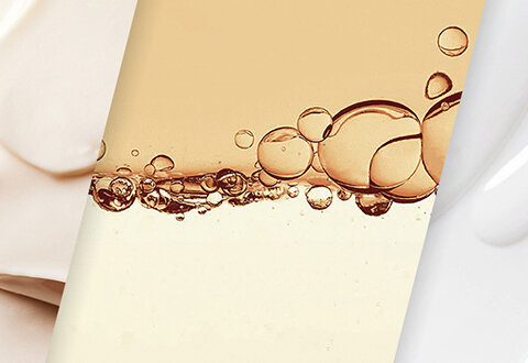 Formula droplets of serum in front of smears of whote moisturizer on a black square background.